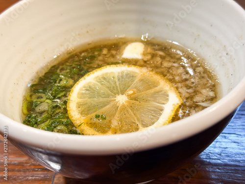 Fototapeta つけ麺のスープ。魚介出汁ベースにネギとあげ玉とレモンをトッピングしたおつゆ。
