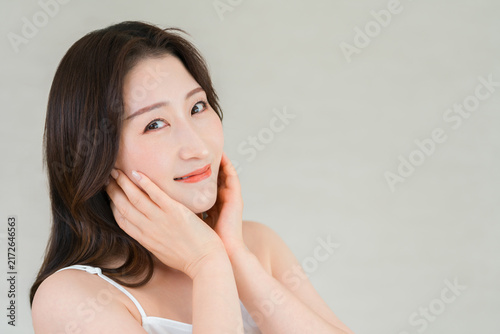 Quadro su tela A middle-aged Asian woman with her hand on her cheek, skincare image