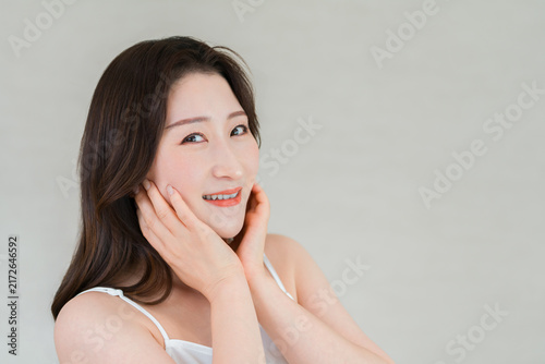 Foto A middle-aged Asian woman with her hand on her cheek, skincare image