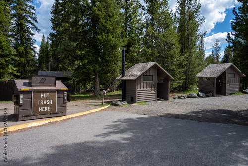 Bear proof garbage can and vault toilets in parking lot at West Thumb Geyser Basin, summer vacation at Yellowstone National Park
