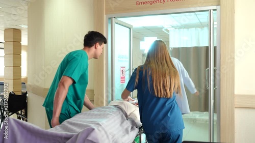 A male and female doctor help push a patient into the emergency room during a patient examination.	