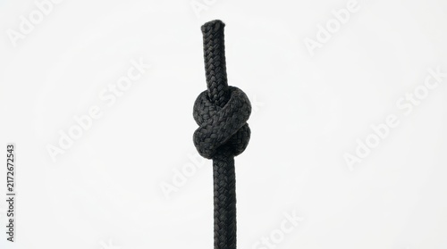 A simple overhand knot tied in a thick black rope isolated on white background
