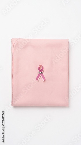 Pink fabric with breast cancer awareness ribbon on white background for health campaign