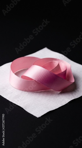 Pink satin ribbon curled on white fabric with dark background for gift wrapping