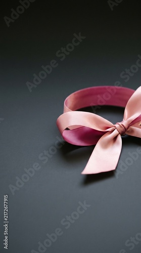 Elegant pink satin ribbon tied in a bow on dark background for gift wrapping