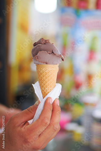 фотографія Person holding a chocolate ice cream cone in hand