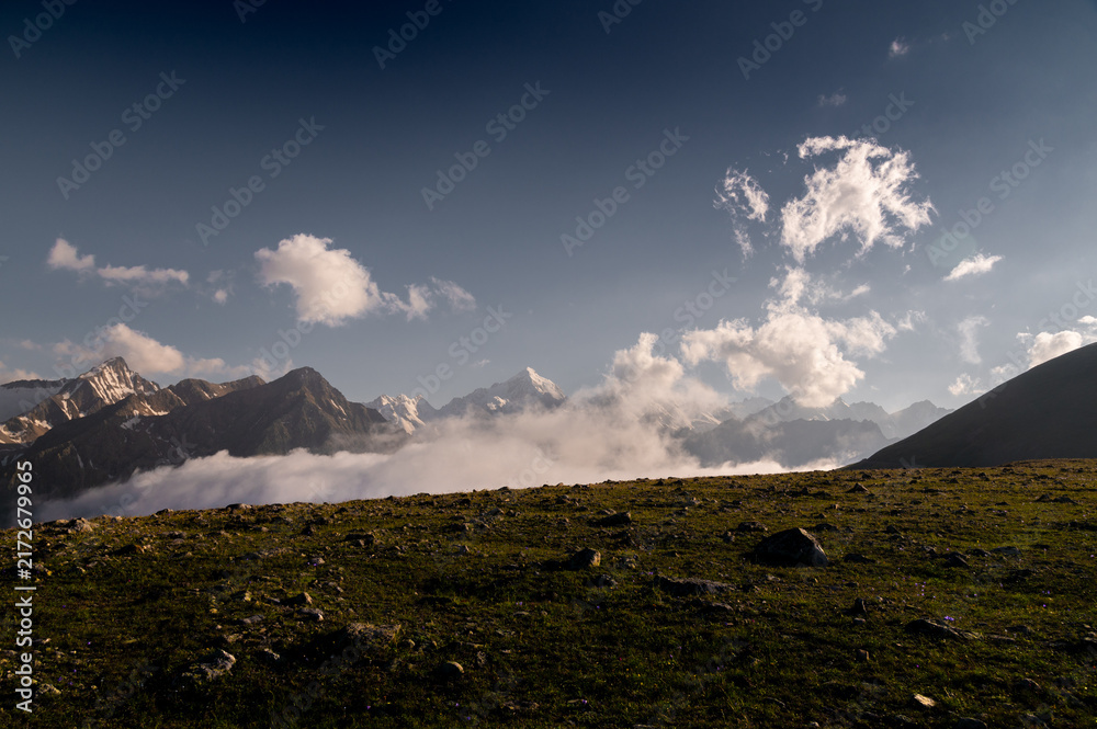 Obraz premium Mountain range with snow capped peaks above low clouds
