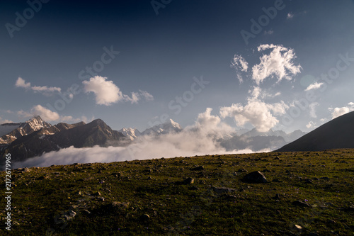 Mountain range with snow capped peaks above low clouds