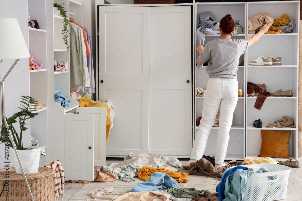 Naklejka premium Home organization and decluttering, woman tidying messy closet and sorting clothes in bedroom for minimalist lifestyle and sustainable living project