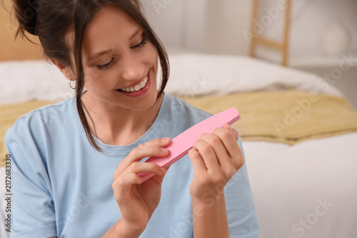 Cuadro en lienzo Self care and beauty routine, young woman filing fingernails with a pink emery b