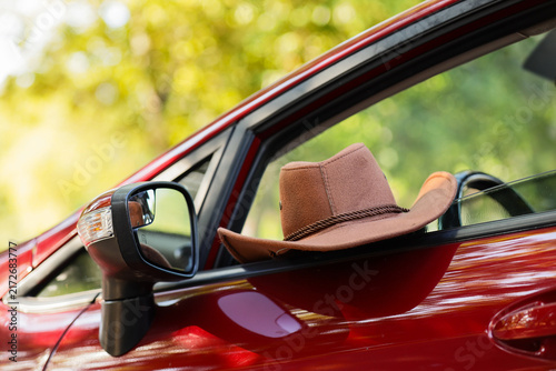 Fotografie Road trip and travel adventure, brown cowboy hat resting on the open window of a