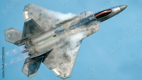 Cuadro en lienzo Fifth generation stealth fighter jet banking hard against a blue sky with vapor