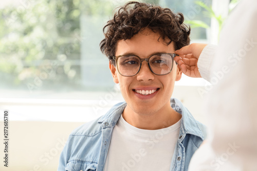 Vision care and eye health, young man trying on new glasses with optometrist ...