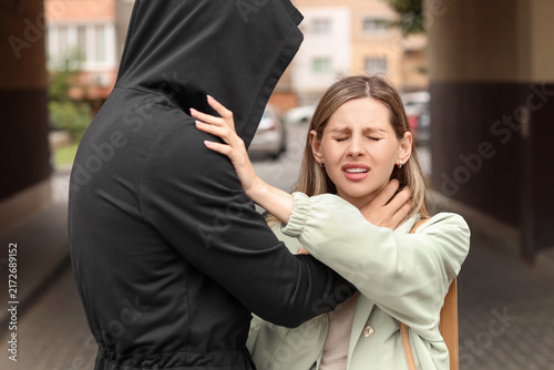 Quadro su tela Personal safety and street crime, woman being attacked by a hooded stranger in a