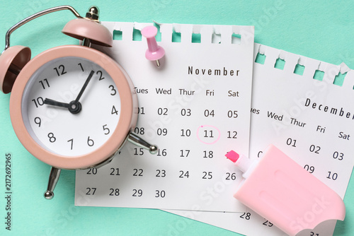 Calendar with alarm clock, paper pin and marker on turquoise background