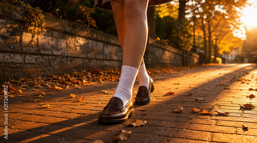 A Nostalgic Autumn Photograph of a Student Walking in Brown Loafers and White Socks Along a Brick Pavement at Sunset