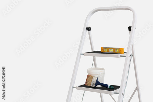 Fotografie Maintenance ladder with paint brush and spirit level near white wall