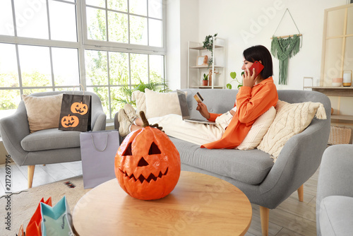 Young woman shopping online for Halloween on sofa at home