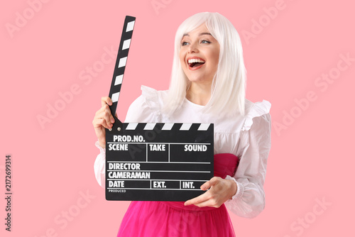 Foto Beautiful actress in wig with movie clapper on pink background