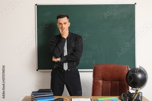 Thoughtful male teacher near chalkboard in classroom