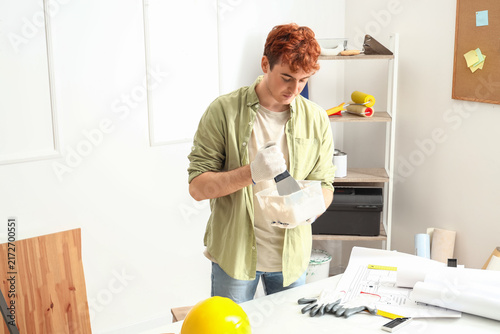 Young man with putty knife and plaster working at home