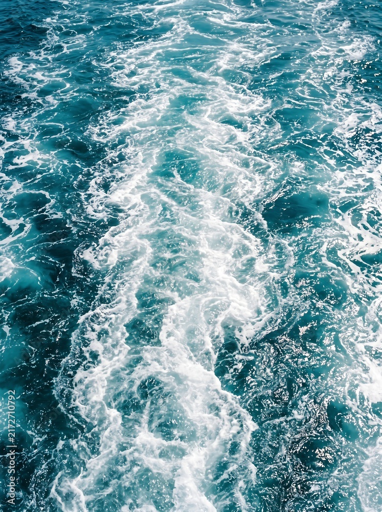 Fototapeta premium Foamy white wake trail behind a fast moving boat in deep blue ocean water with movement turbulence propeller navigation seascape daylight