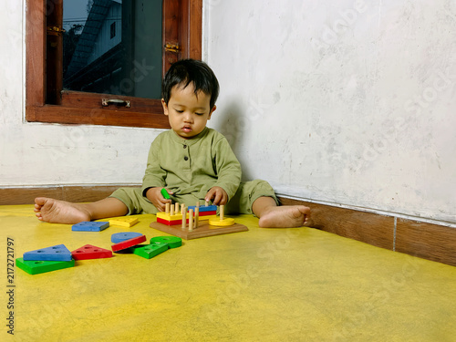 Принти на полотні Portrait photo of a toddler playing with colorful wooden shape sorting blocks on