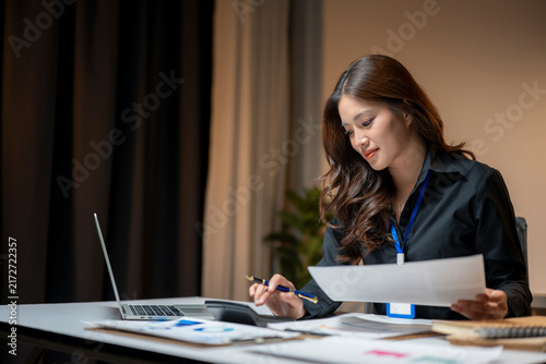 Businesswoman calculating financial data with papers and laptop at office working