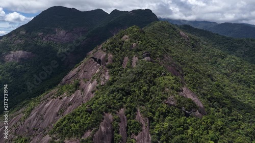 Slow High-Altitude Drone Approach Toward a Majestic Wild Mountain on Khanh Le Pass, Khanh Hoa, Vietnam, Covered in Dense Forest Beneath Dark Storm Clouds and Dramatic Sunlight