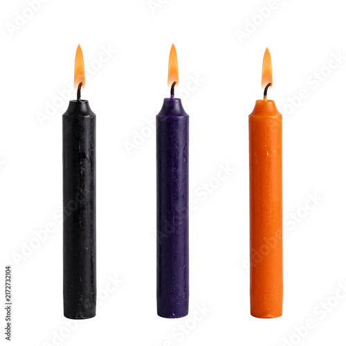 Obraz na płótnie Three lit taper candles in black purple and orange colors.