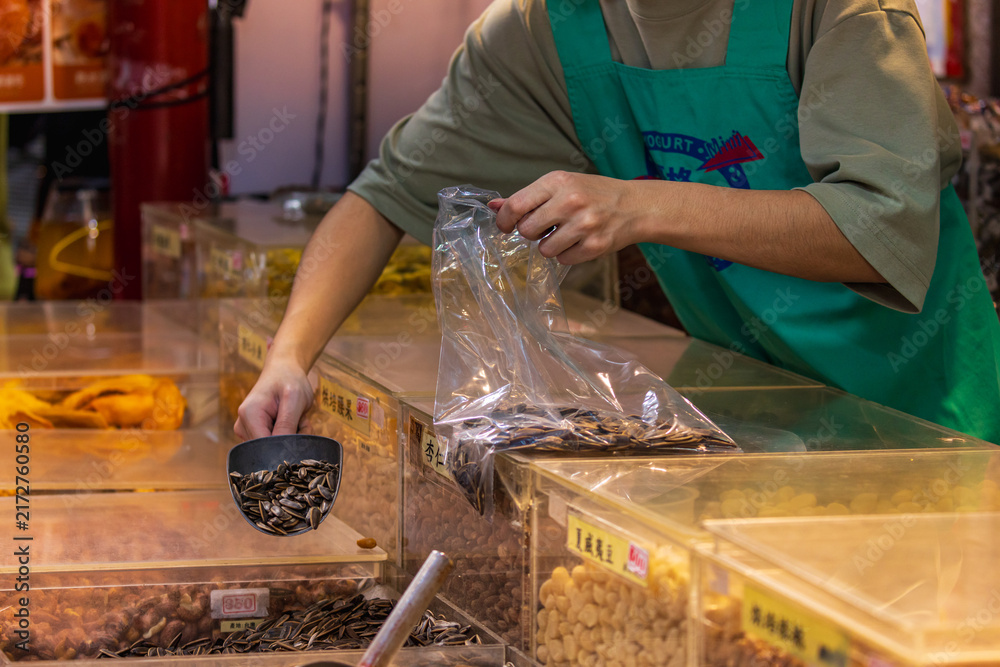 Obraz premium Vendor Bags Sunflower Seeds at Dihua Street Market