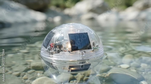 Solar Technology Sphere Floating Clean Water Device with Transparent Design, Natural Reflections, Visible Stones, Gentle Ripples, and Sensor