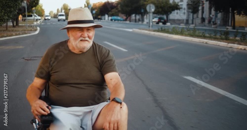 Medium close view of an elderly man driving his electric wheelchair through the city, showing independent mobility, confidence and active everyday life.