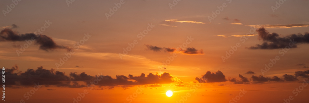 Fototapeta premium Panoramic golden sunset sky background with glowing sun disk and orange clouds