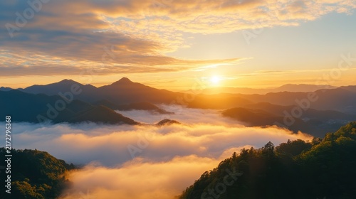 Sunrise Over Misty Mountains: The golden sun rises over a picturesque mountain range, casting a warm glow on a sea of clouds that blankets the valleys below.