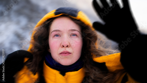 Photography Female mountaineer shielding her face from strong wind and blowing snow during a challenging winter ascent in the mountains