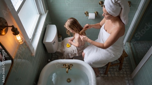 Mother Brushing Daughter’s Wet Hair After Bath in Vintage Mint Green Bathroom Overhead View