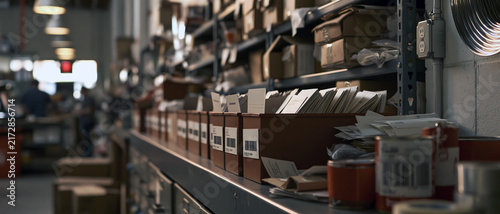 Commercial warehouse inventory aisle with storage bins, cardboard box, paper file, shelf, and industrial supplies creating organized logistics workspace