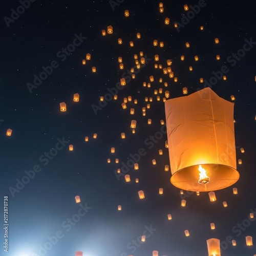 Floating paper lanterns illuminate the night sky.