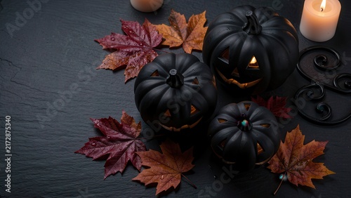 moody halloween flat lay of black carved pumpkins and autumn leaves on dark slate for seasonal marketing