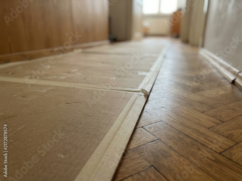 Protective cardboard shielding a classic herringbone parquet floor during residential home renovation and interior improvement
