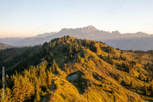 Majestic alpine mountain peaks illuminated by warm golden sunrise light, creating a breathtaking summer landscape in the Austrian Alps, perfect for travel, tourism and premium nature imagery.