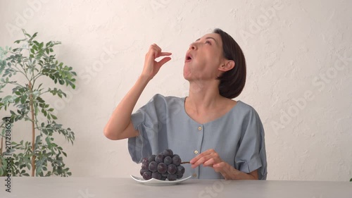 リビングでぶどうを食べる女性