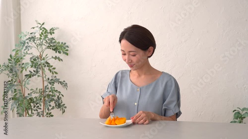 リビングで柿を食べる女性
