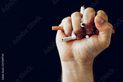 Fotografie Determined hand crushing cigarettes in a fist as a symbol of quitting smoking fo