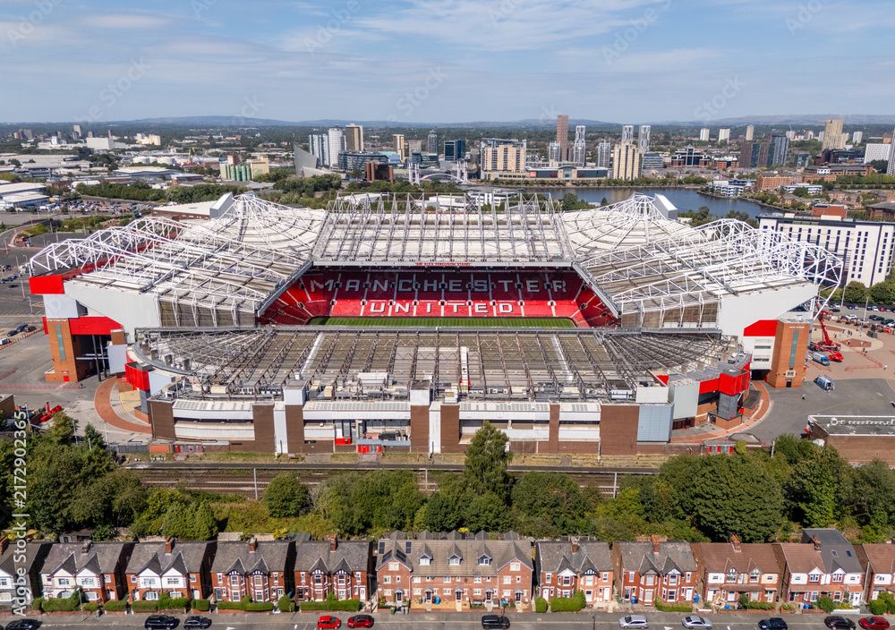 Fototapeta premium Old Trafford football stadium and Salford Quays in Greater Manchester, England, seen from above with the surrounding urban landscape.