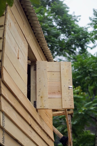 Simple wooden shutter window opened on a plank wall cabin house in the forest area.