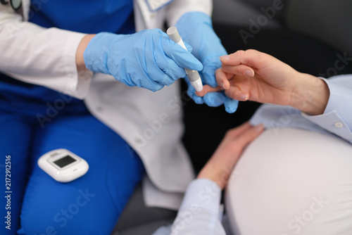 Fotografie Skilled doctor carefully checks blood sugar level of pregnant woman
