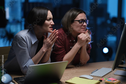 Bild auf Leinwand Businesswomen anxiously watch information on computer screen during late office work