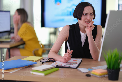 Принти на полотні Female office worker with short dark hair anxiously looks at computer monitor